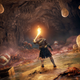 A warrior holds up a torch to illuminate a cavern filled with giant ants.